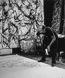 Black and white photo of a man splashing paint on the floor and wall