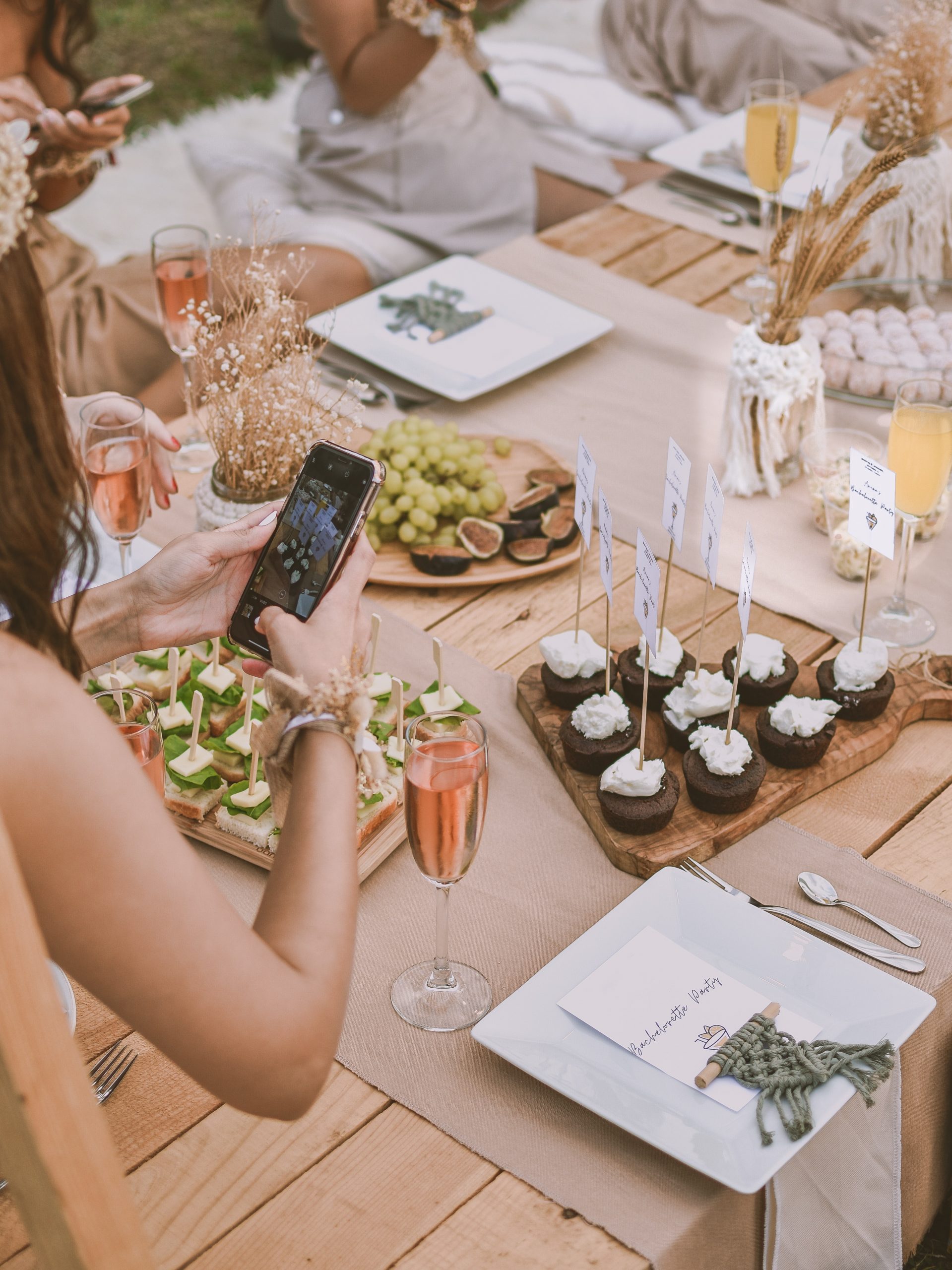 A woman taking a picture of the food at a table at a party