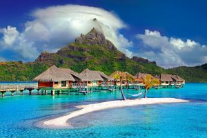 Scenic photo of houses over the ocean with a large mountain in the background