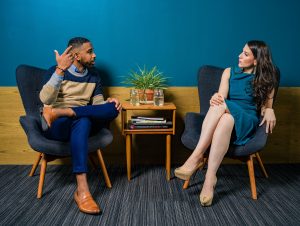 Two people sitting in chairs talking to each other