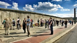Photo of people walking in-front of the Berlin Wall.