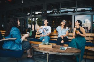 Photo of four friends conversing at a coffee shop.