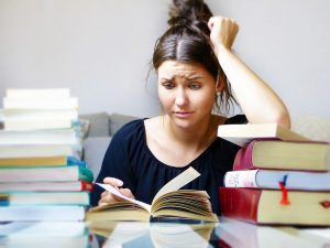 Photo of a stressed student surrounded by books.